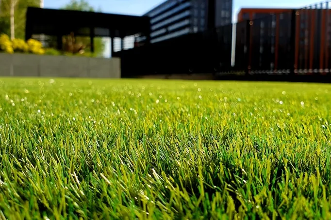 Close view of dense, evenly cut artificial turf in a landscaped yard.