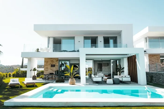White modern house with a swimming pool and palm planting.